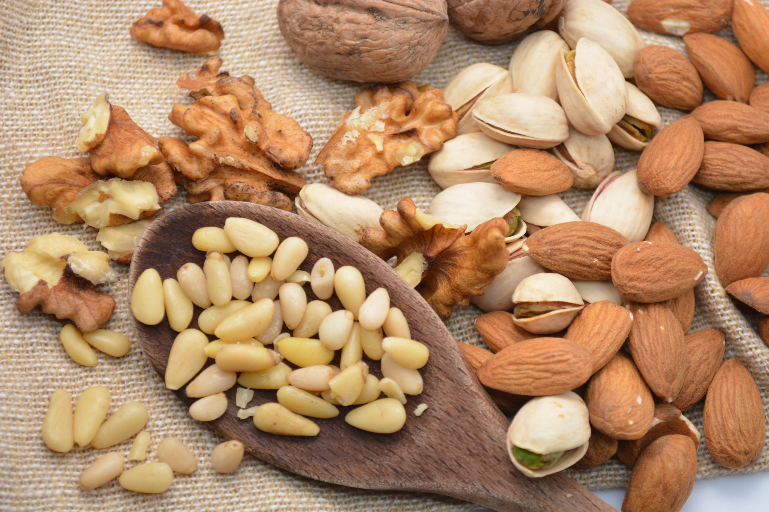 frutta secca varia noci pistacchi mandorle pinoli su cucchiaio da cucina di legno